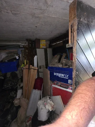Cluttered garage full of tools, boxes and household items before clearance