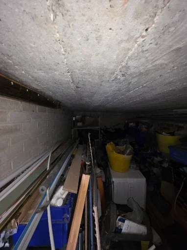 Garage shelving stacked with crates and household items before clearance