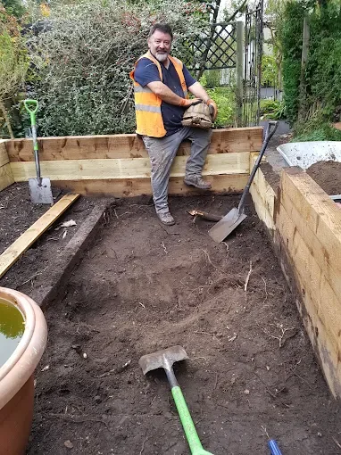 Team member working on a raised garden bed during a garden clearance project