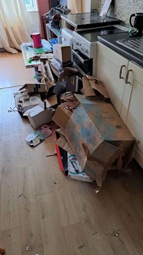 Kitchen floor covered in packaging and waste before clearance